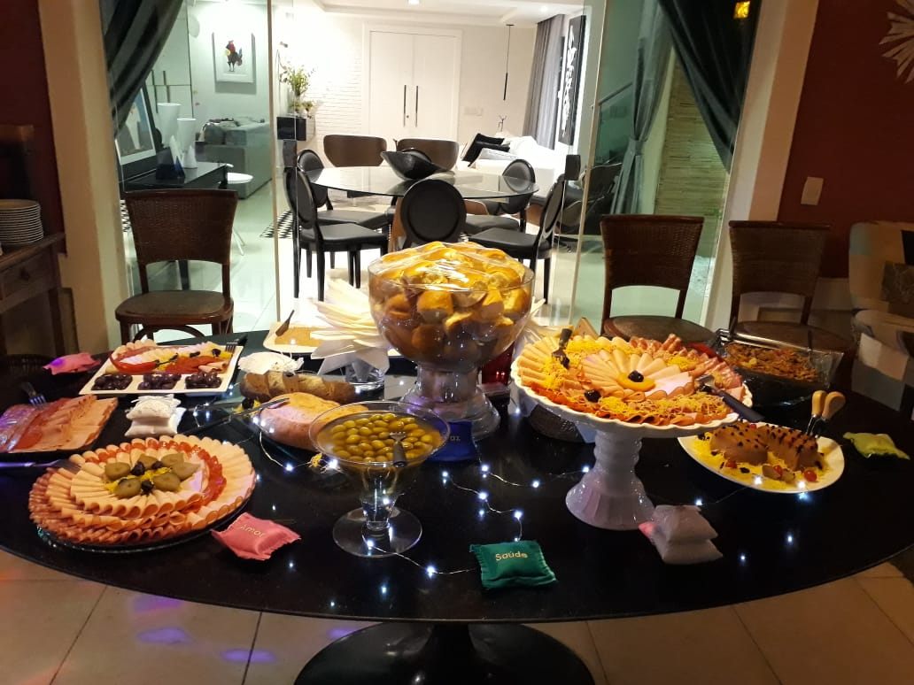 Mesa de buffet montada com frios, frutas e petiscos sob luzes cintilantes