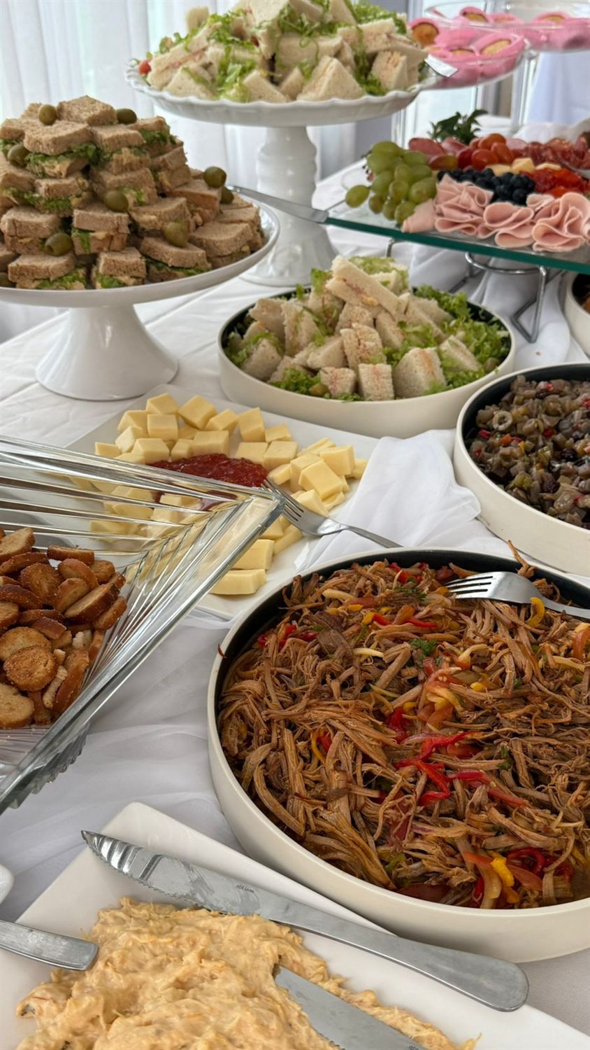 Sanduíches, macarrão e saladas em uma mesa de buffet